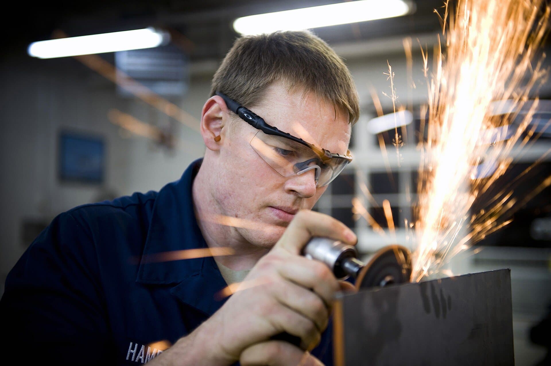 Metalworker grinding a sheet of metal in a shop