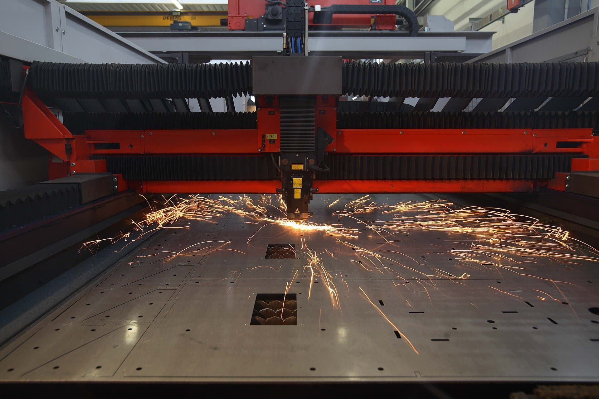 Laser cutting machine throwing sparks as it cuts a steel sheet