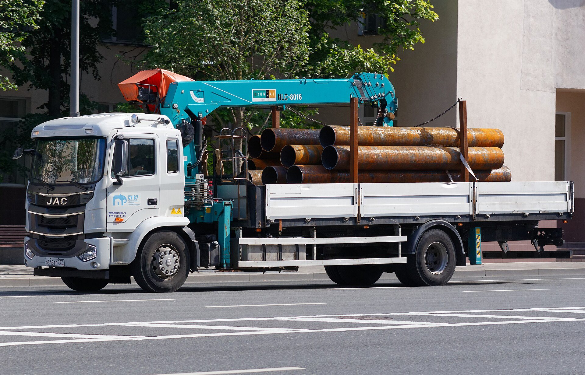 Crane truck carrying a load of steel through a city street