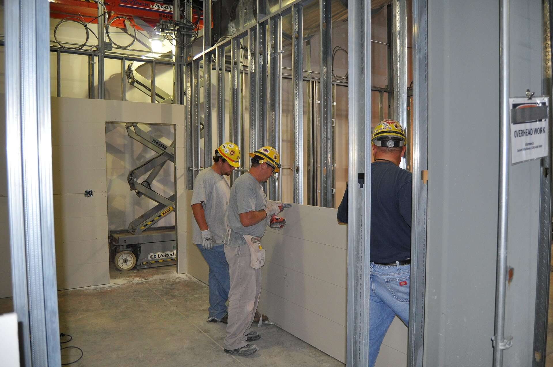 Crew installing drywall on metal stud walls